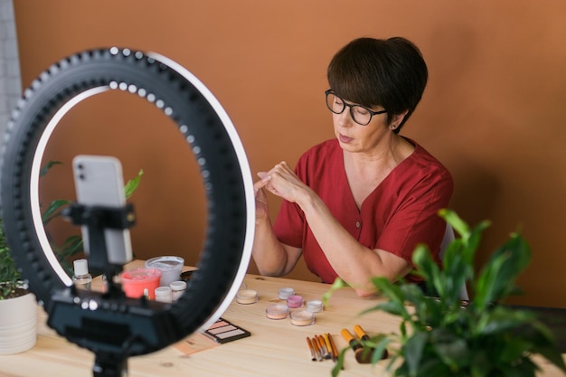 Concepto de comercio electrónico y blogs de belleza y cosmética mujer madura profesional maquilladora testi