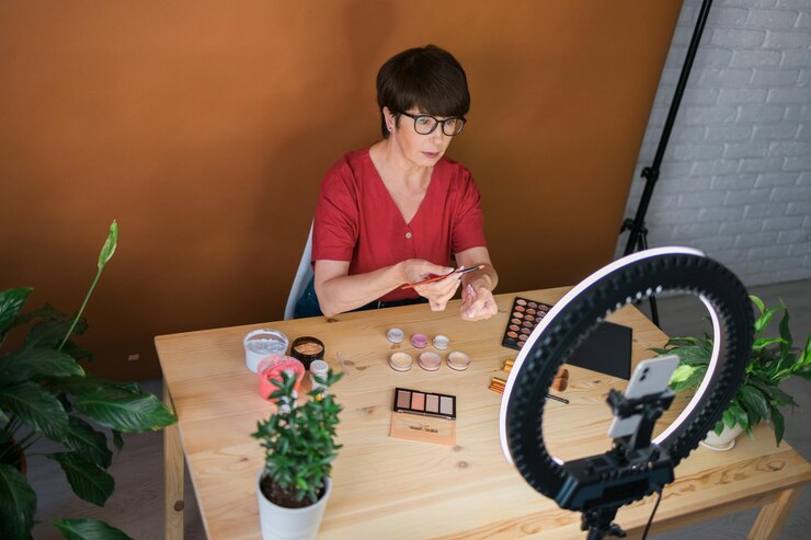 Foto concepto de comercio electrónico y blogs de belleza y cosméticos maquilladora femenina madura profesional probando nuevos cosméticos grabando revisión de video sobre productos cosméticos en casa