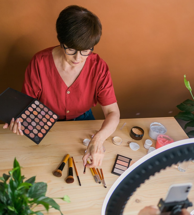 Foto concepto de comercio electrónico y blogs de belleza y cosméticos maquilladora femenina madura profesional probando nuevos cosméticos grabando revisión de video sobre productos cosméticos en casa