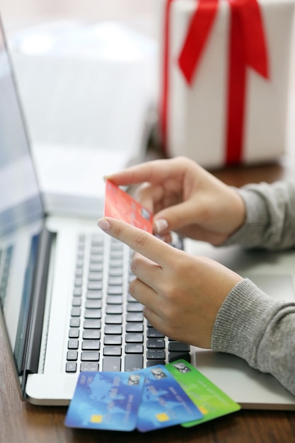 Concepto de comercio electrónico Mujer con tarjeta de crédito portátil y caja de regalo de cerca