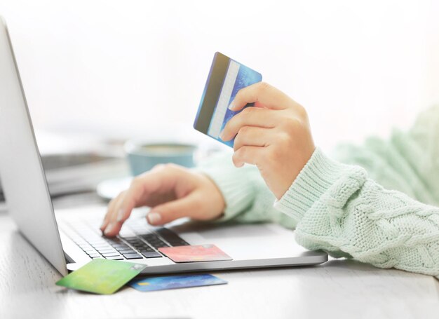 Concepto de comercio electrónico Mujer con tarjeta de crédito portátil y taza de café de cerca