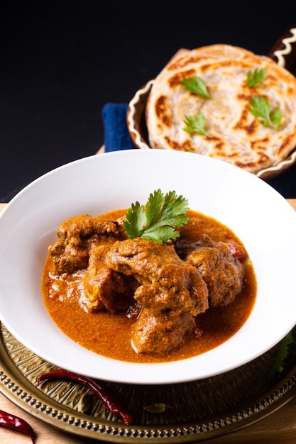 Concepto de comida casera de ternera al curry masala y roti paratha sobre tabla de madera con espacio de copia