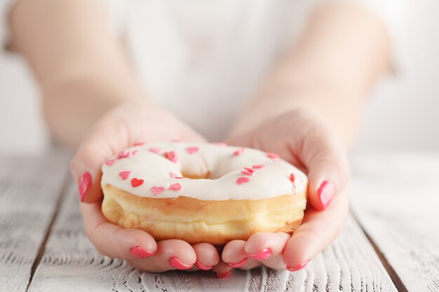 Concepto de comida chatarra y comer - cerca de mano femenina donut glaseado