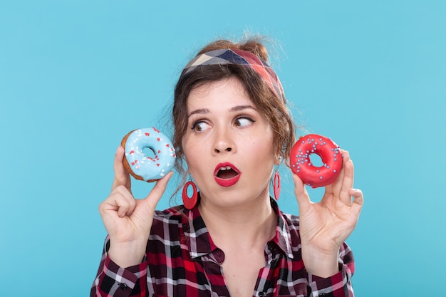 Foto concepto de comida chatarra, dieta y estilo de vida poco saludable - mujer pin-up con donas sobre el azul