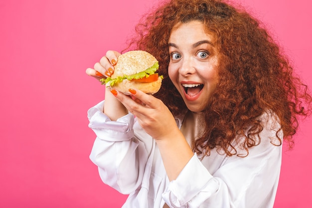 Concepto de comida chatarra con mujer joven sosteniendo una hamburguesa