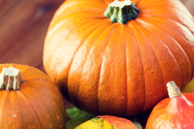 Concepto de comida, cosecha, temporada y otoño: cierre de calabazas en una mesa de madera en casa