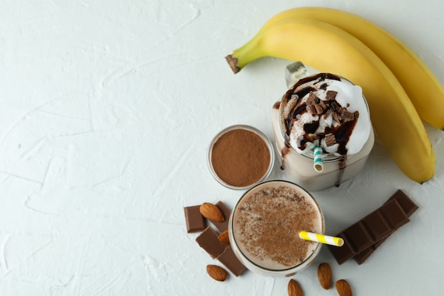 Concepto de comida deliciosa con batido de chocolate y plátano en la mesa con textura blanca