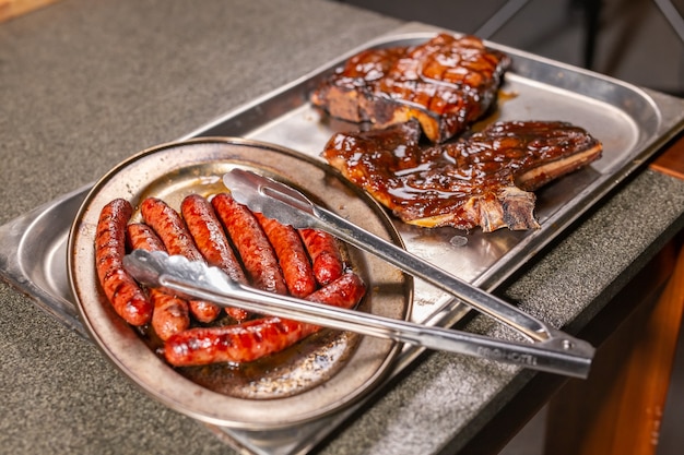 Concepto de comida, deliciosa y carne: asar salchichas de carne de caballo a la parrilla.