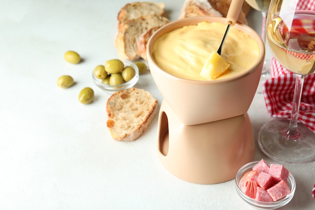 Concepto de comida deliciosa con fondue en mesa con textura blanca