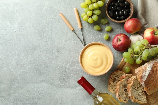 Concepto de comida deliciosa con fondue en mesa con textura gris