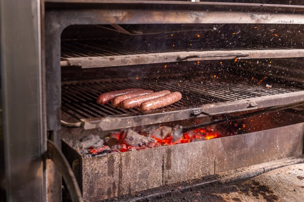 Concepto de comida, delicioso y artesanal: salchicha a la parrilla a la parrilla en llamas.