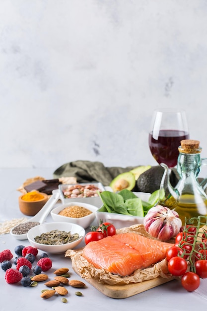 Concepto de comida de dieta equilibrada Surtido de alimentos saludables colesterol bajo espinacas aguacate vino tinto té verde salmón tomate bayas semillas de chía lino cúrcuma ajo nueces aceite de oliva Fondo del espacio de copia