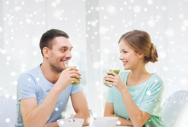 concepto de comida, hogar, gente y felicidad - pareja sonriente desayunando en casa