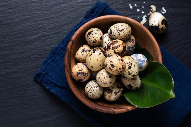 Concepto de comida Huevos de codorniz en tazón de madera sobre fondo de piedra pizarra negra con espacio de copia