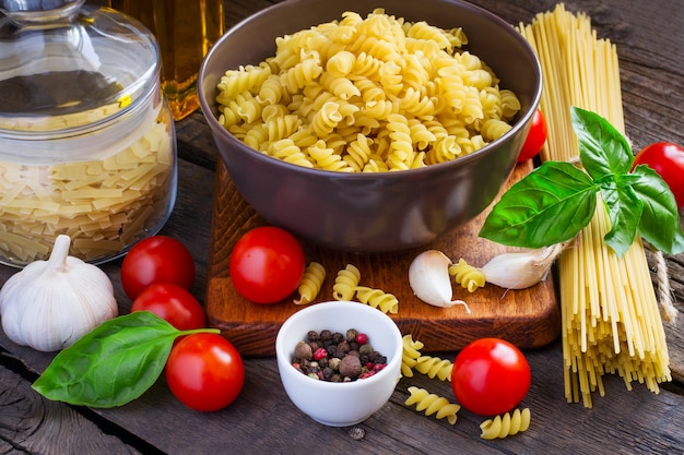 Concepto de comida italiana - pasta, tomates cherry, especias sobre un fondo de madera
