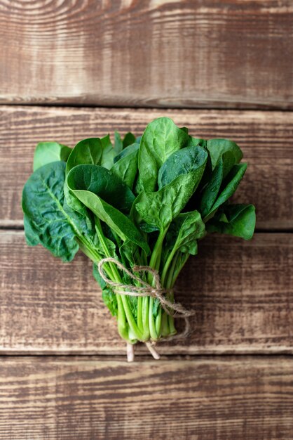 Concepto de comida limpia. Hojas de hojas verdes de espinacas orgánicas recién cosechadas jugosas maduras sobre un fondo de madera