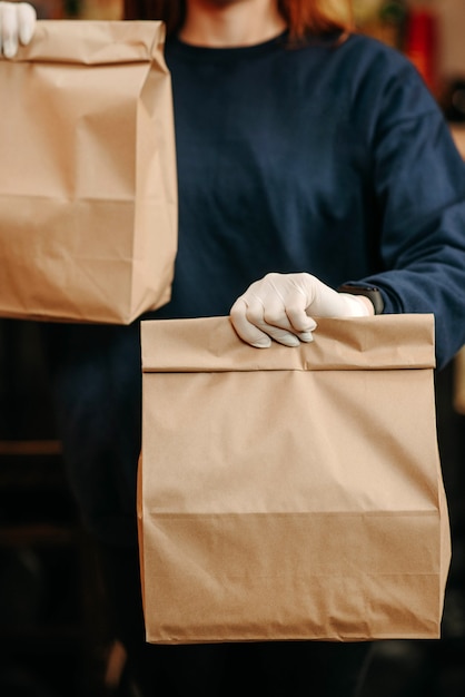 Concepto de comida para llevar. Chica en guantes blancos tiene comida para llevar envasada