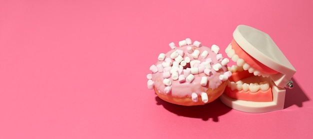 Concepto de comida mala para los dientes sobre fondo rosa