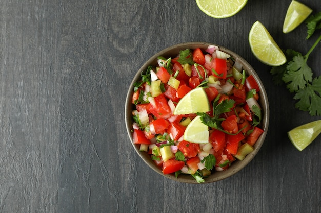 Concepto de comida mexicana con Pico de Gallo en mesa de madera oscura.