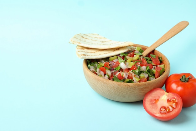 Concepto de comida mexicana con Pico de Gallo sobre fondo azul.