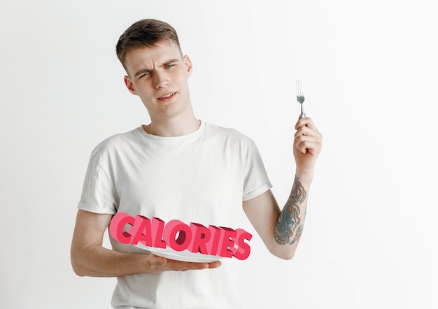 Concepto de comida. Modelo sosteniendo un plato con letras de calorías.