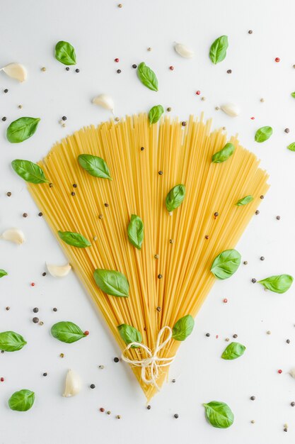 Concepto de comida con pasta, albahaca, ajo y pimienta en blanco