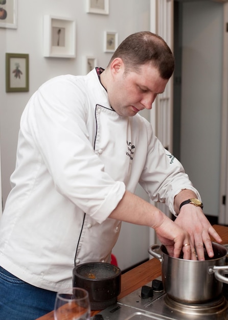 Concepto de comida y personas chef masculino con comida cocinada de pie en la cocina