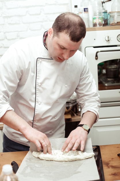 Concepto de comida y personas chef masculino con comida cocinada de pie en la cocina