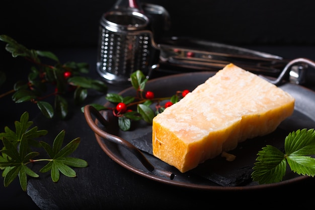 Concepto de comida queso parmesano orgánico en bandeja de hierro rústico sobre fondo de piedra pizarra negra con espacio de copia