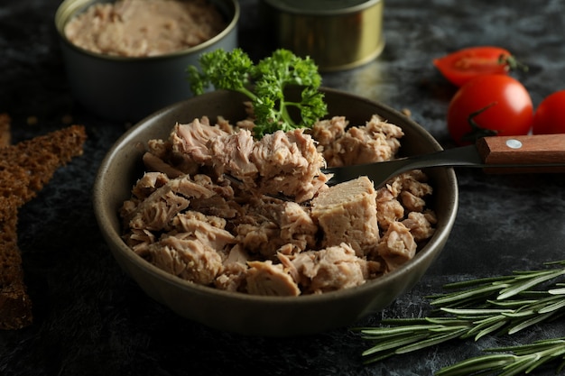 Concepto de comida sabrosa con atún enlatado sobre fondo negro ahumado