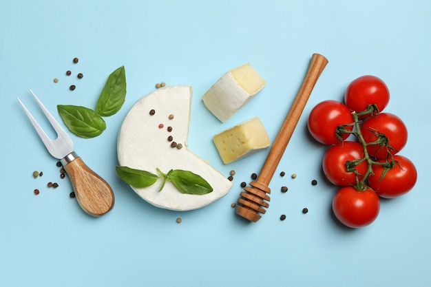 Concepto de comida sabrosa con camembert y especias sobre fondo azul.