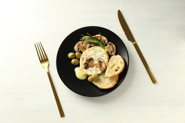 Concepto de comida sabrosa con camembert a la parrilla sobre fondo blanco de madera.