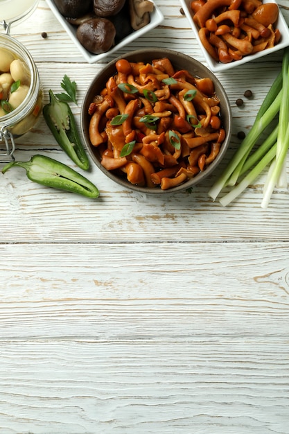 Concepto de comida sabrosa con champiñones marinados en mesa de madera