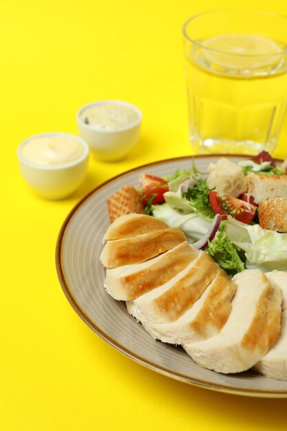 Concepto de comida sabrosa con ensalada César sobre fondo amarillo