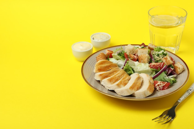 Concepto de comida sabrosa con ensalada César sobre fondo amarillo