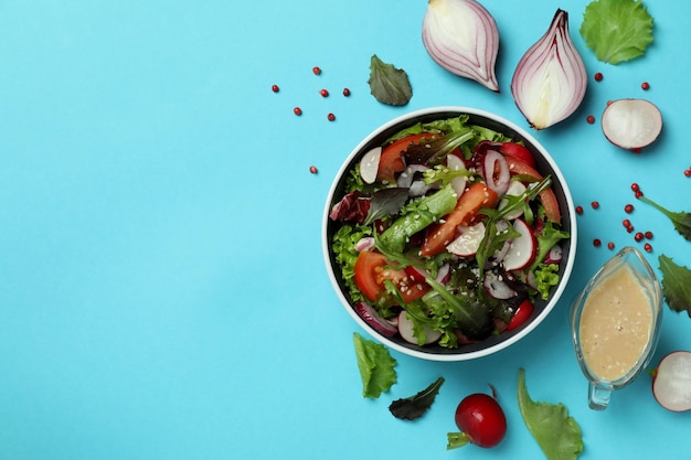 Concepto de comida sabrosa con ensalada de verduras con salsa tahini sobre fondo azul.