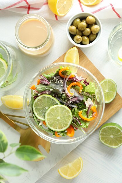 Concepto de comida sabrosa con ensalada de verduras con salsa tahini sobre fondo blanco de madera