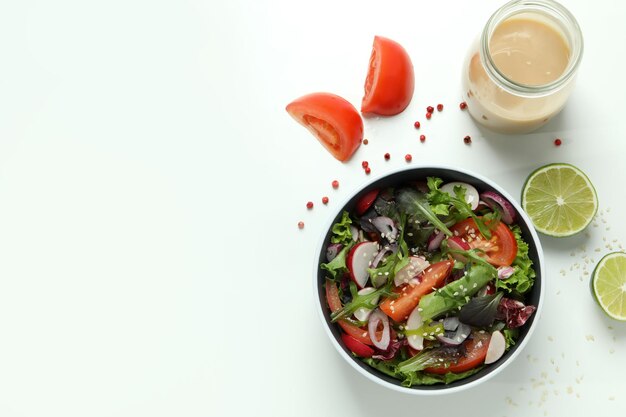 Concepto de comida sabrosa con ensalada de verduras con salsa tahini sobre fondo blanco.