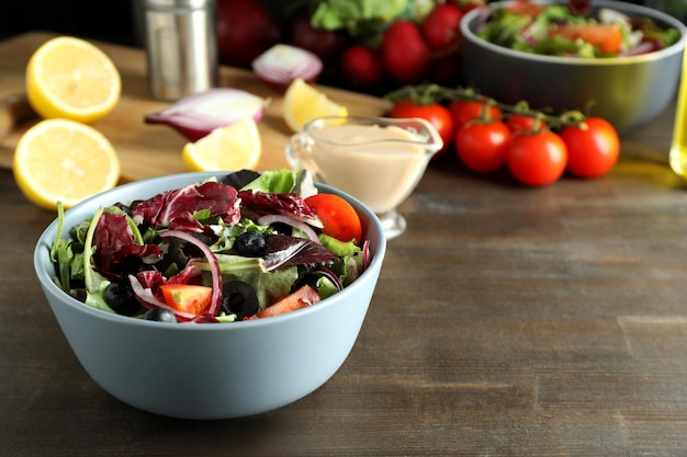 Concepto de comida sabrosa con ensalada de verduras con salsa tahini sobre fondo de madera