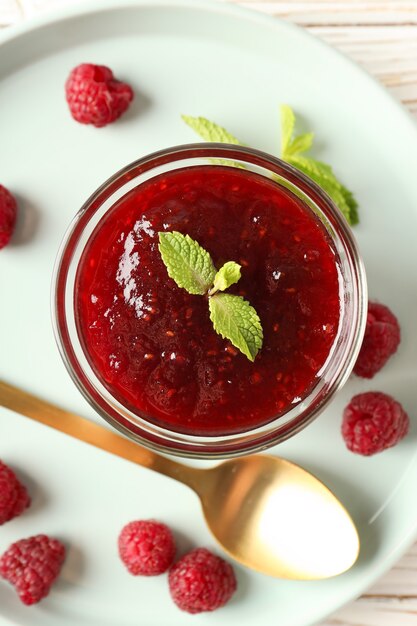 Concepto de comida sabrosa con mermelada de frambuesa sobre fondo blanco de madera