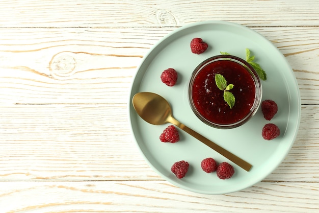 Concepto de comida sabrosa con mermelada de frambuesa sobre fondo blanco de madera