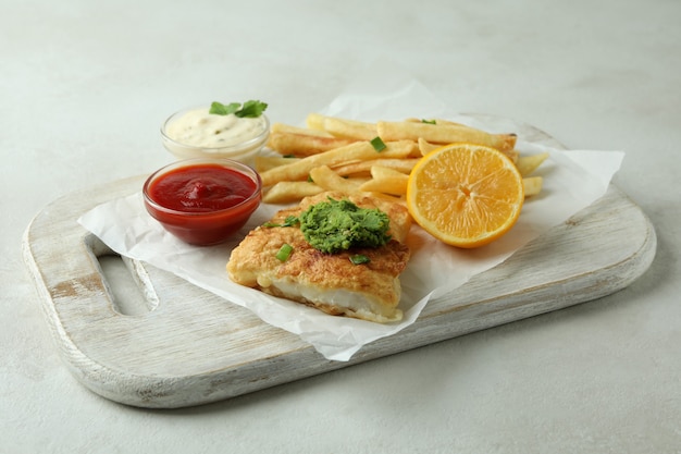 Concepto de comida sabrosa con pescado frito y patatas fritas en la mesa con textura blanca