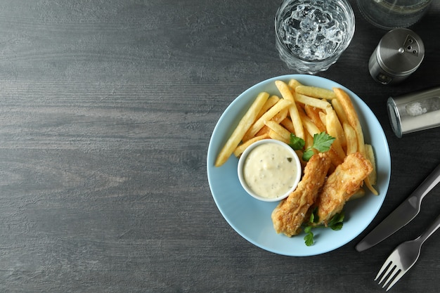 Concepto de comida sabrosa con pescado frito y patatas fritas en la mesa de textura oscura