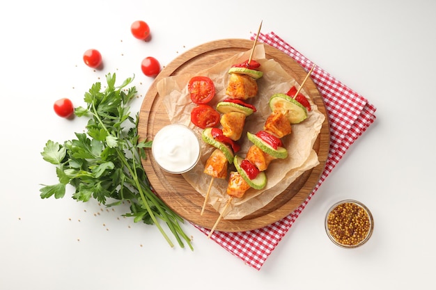 Concepto de comida sabrosa con pinchos de pollo sobre fondo blanco.