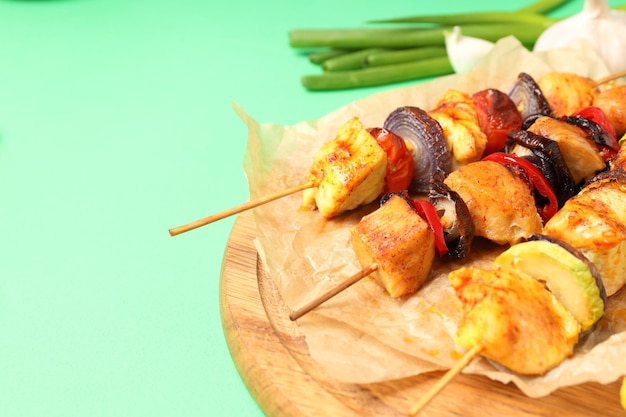 Concepto de comida sabrosa con pinchos de pollo sobre fondo verde