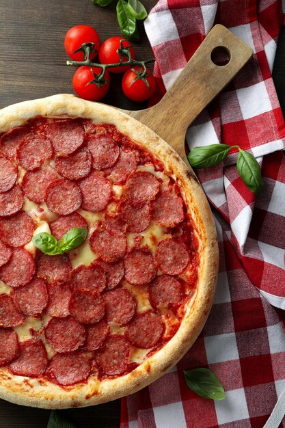 Concepto de comida sabrosa con pizza de salami sobre fondo de madera