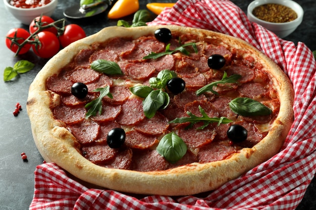 Concepto de comida sabrosa con pizza de salami sobre fondo oscuro