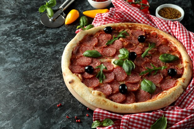 Concepto de comida sabrosa con pizza de salami sobre fondo oscuro