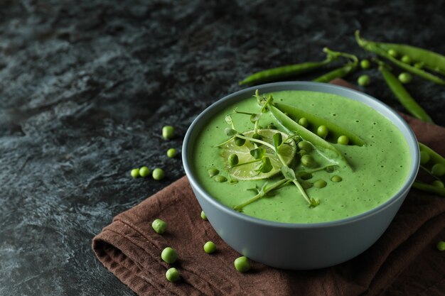 Concepto de comida sabrosa con sopa de guisantes en mesa ahumada negra