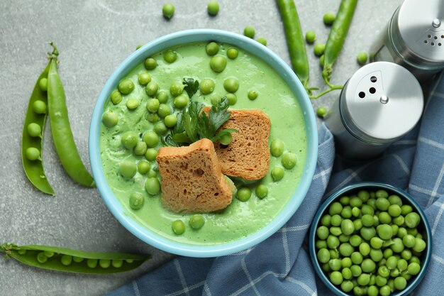 Concepto de comida sabrosa con sopa de guisantes en mesa con textura gris